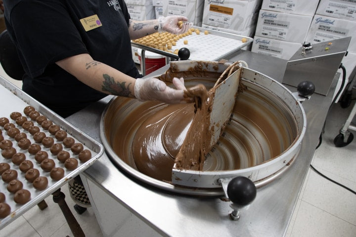 Employee at Hansel and Gretel Candy Kitchen coating candies with chocolate